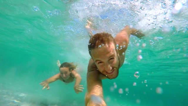 Young couple take selfie portrait underwater with action camera