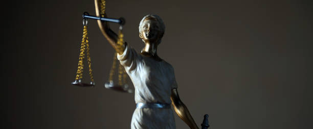 istock Justice Themis goddess sculpture on dark brown background. 1002905216