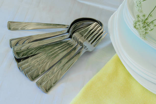 Fresh white and yellow tableware set: napkins,plates, silver utensils and a delicate flowers