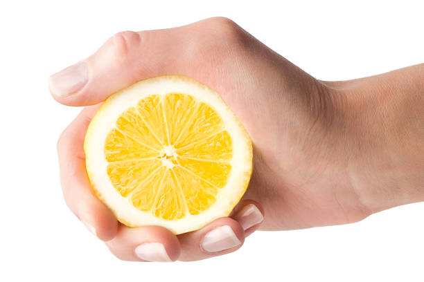 istock Hand squeezes lemon juice on a white background, isolated 1002909130