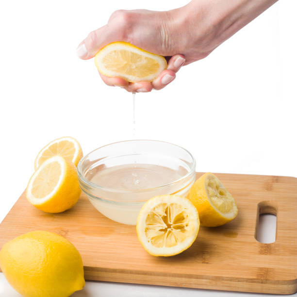 istock Hand squeezes lemon juice on a white background, isolated 1002911254