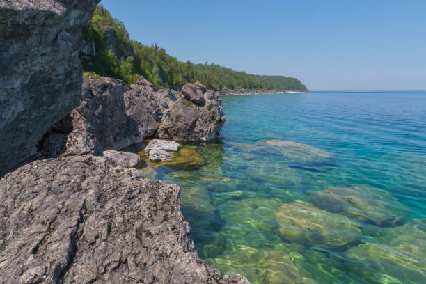 istock Bright clear aqua green water on Bruce Peninsula with big limestone rocks 1002914154