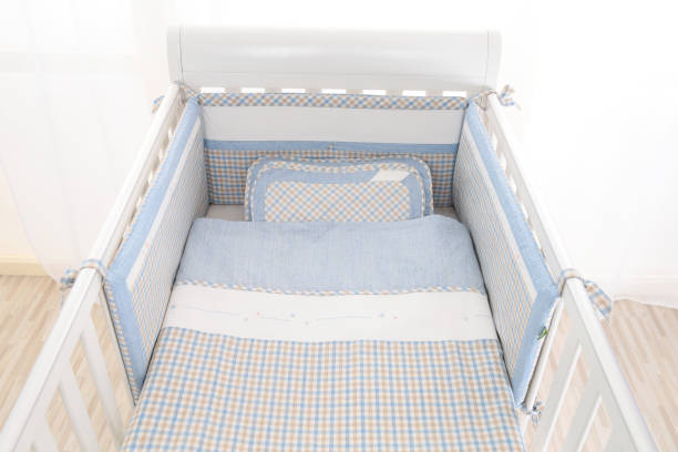 Cozy baby cot with white square pillows and patchwork comforter blanket with stars and black stripes