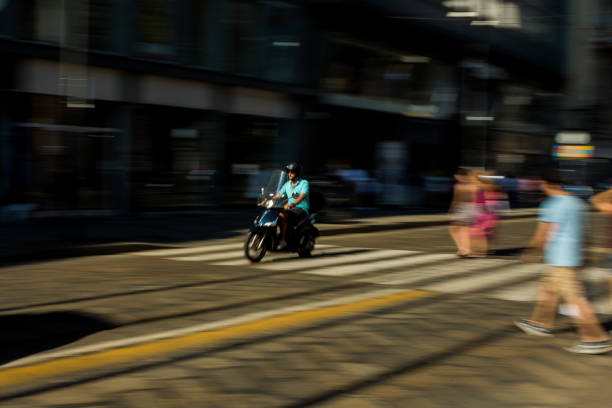 Vespa or scooter is an international icon or symbol for Italy. This picture was taken on a hot summer afternoon on July 15 2018 in Milano, Lombardy as this man was seen riding through the streets of Milan in his vespa.