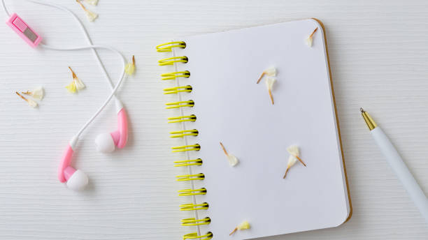 istock Earphones and notebook with flower on white table 1002922806