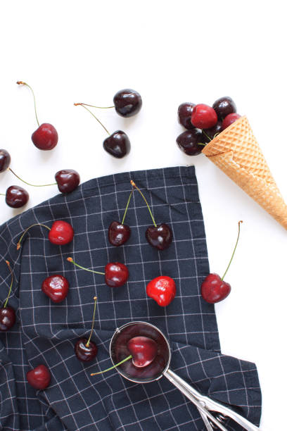 istock Ice cream concept Fresh cherries and waffle cone on checkered napkin Ice cream spoon White backgroud Summer fruits Harvesting Organic fruits Copy space Top view 1002933080