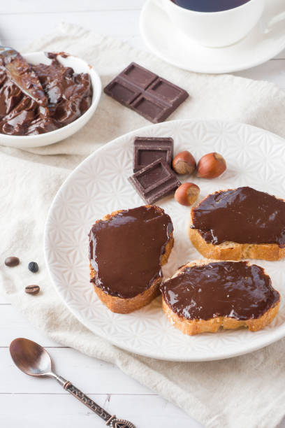 istock Sandwiches with chocolate hazelnut spread on the plate. Cup of coffee on the table. 1002933482