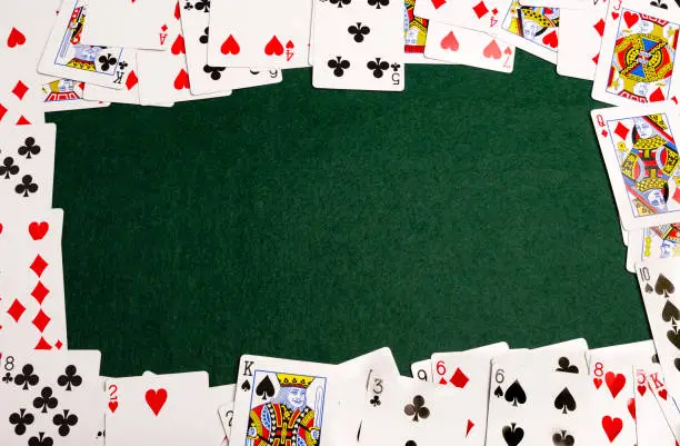 Playing-cards spread out to form a frame on a green baize background