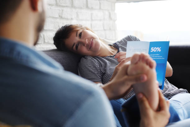 istock Man Massaging Girlfriend Feet On Sofa At Home 1002945092