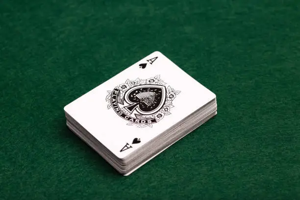 A deck of playing-cards face up on a green baize background with the ace of spades uppermost