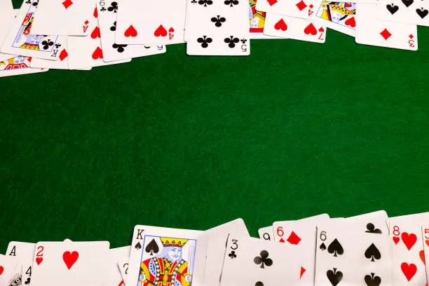 Playing-cards spread out on a green baize cloth to form two sides of a frame