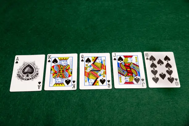 The highest value hand in poker, a royal flush, laid out on a green baize cloth