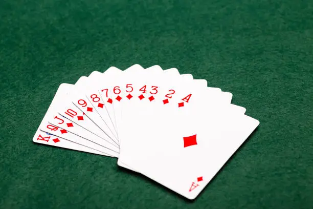 A full suit of thirteen Diamonds playing-cards laid out in a fan shape on a green baize background