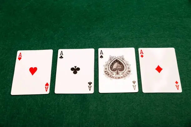 All four aces from a pack of playing-cards laid out in a row on a green baize cloth