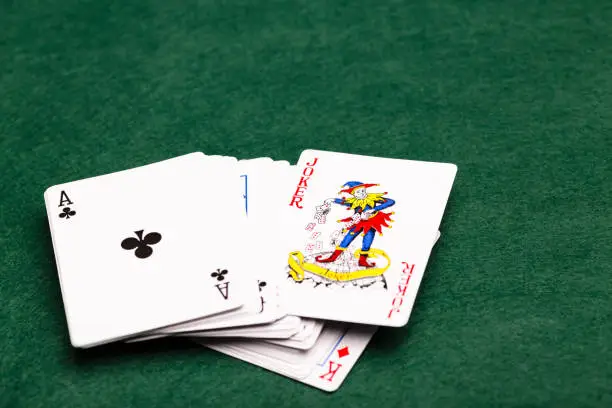 Deck of cards face-up on a green baize with the Joker poking out of the middle