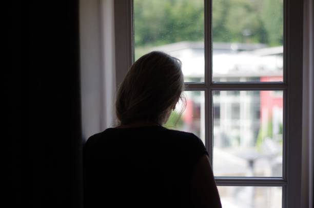 istock Woman standing in window 1002977944