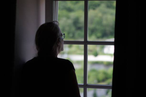 istock Woman standing in window 1002977946