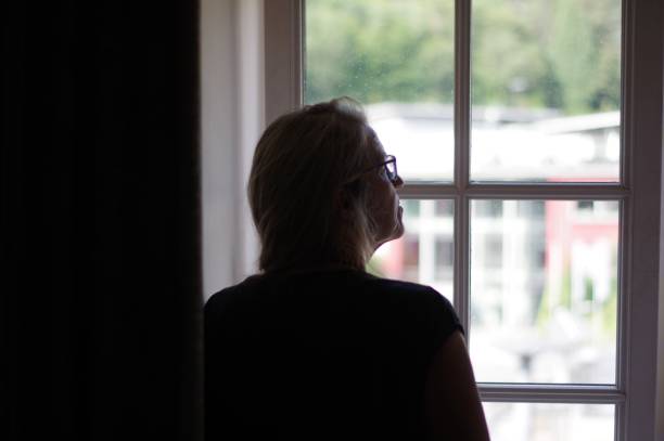 istock Woman standing in window 1002977970
