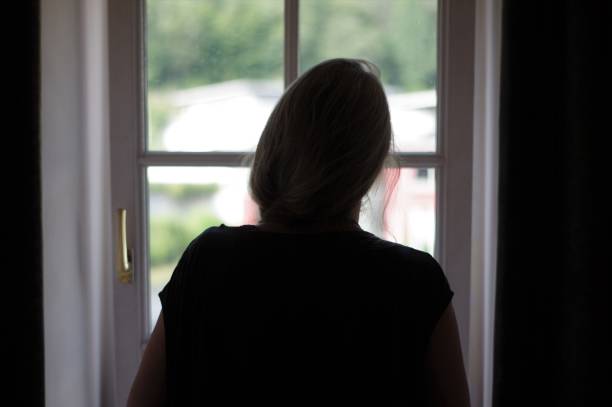 istock Woman standing in window 1002978008
