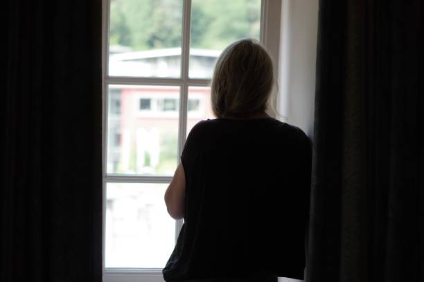 istock Woman standing in window 1002978020