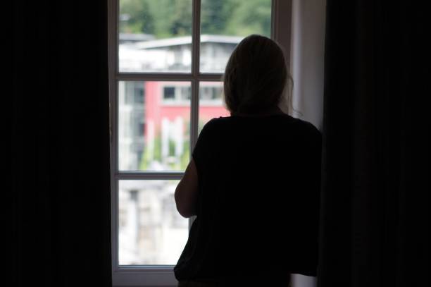 istock Woman standing in window 1002978022