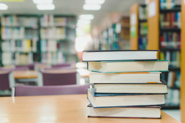 istock Book stack in the library room and blurred bookshelf for business and education background, back to school concept 1002986694