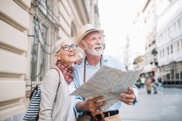 senior pareja sosteniendo un mapa y mirando a la distancia - couple vacations travel destinations europe fotografías e imágenes de stock