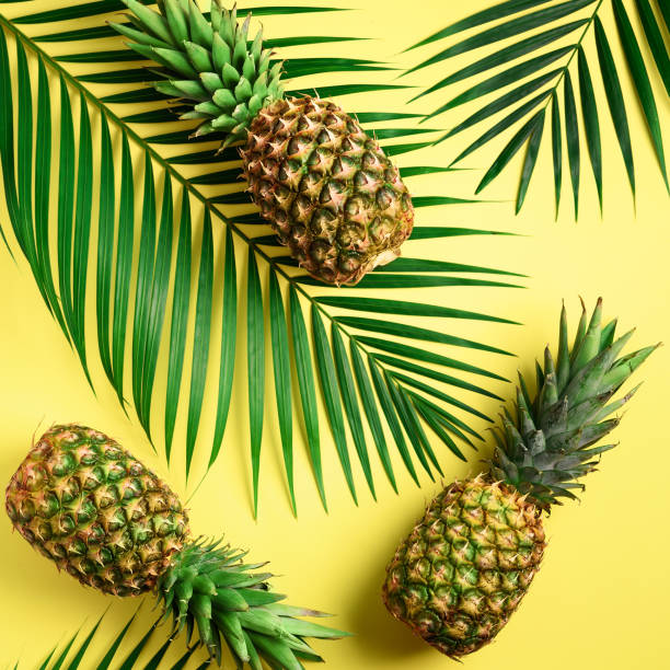 istock Pineapple and tropical palm leaves on yellow background. Top view. Summer concept. Creative flat lay with copy space 1002989352