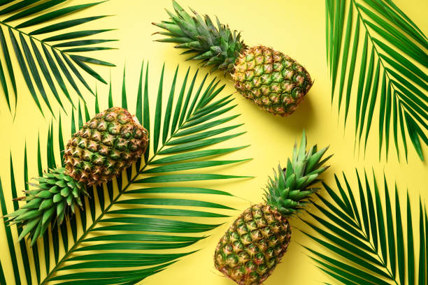 istock Pineapple and tropical palm leaves on yellow background. Top view. Summer concept. Creative flat lay with copy space 1002989398