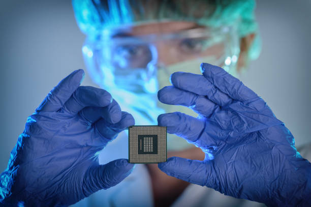 The engineer holds a processor in hands An engineer working in a laboratory wearing a special uniform and protective gloves holds new processor in hands and examines it nanotechnology photos stock pictures, royalty-free photos & images