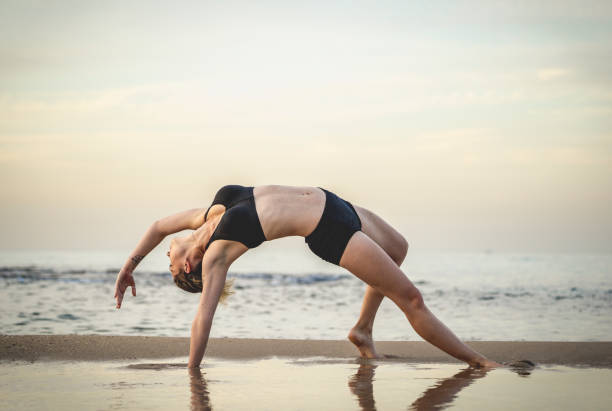 Young Woman Practicing Yoga On The Beach stock photo