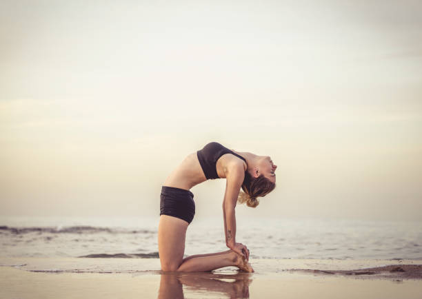 Young Woman Practicing Yoga On The Beach stock photo