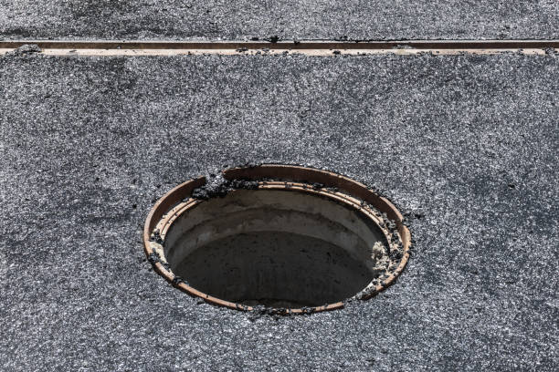 A deep manhole without a cover on the road while laying a new asphalt presents a danger to pedestrians and cars A deep manhole without a cover on the road while laying a new asphalt presents a danger to pedestrians and cars sewer lid stock pictures, royalty-free photos & images