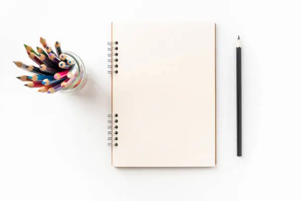 Design concept - Top view of kraft spiral notebook, blank page, pen holder and color pen isolated on white background for mockup