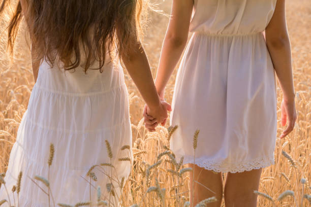 istock Two girls standing together on wheat field, closeup 1003000256