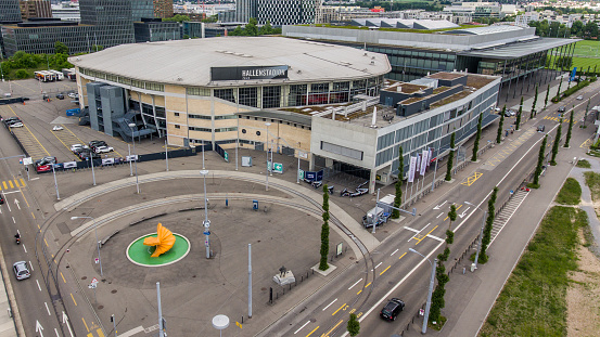 Zurich, Switzerland - May 22, 2018: View of the Zurich Hallenstadion, as well as the Zurich exhibition center behind it. In front of the indoor stadium is the ZSC Lions square with the well-known yellow fountain.