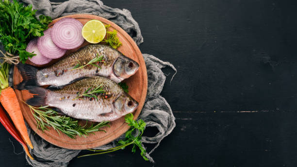 istock Raw Fish with Spices and Vegetables. Carp On a wooden background. Top view. Copy space. 1003064000