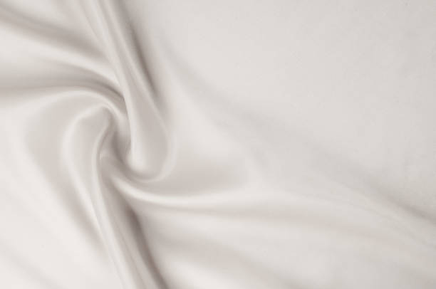istock Texture background of fabric. White fabric. Silk fabric wallpaper texture background in sepia pastel white shade: Lovely natural silk textured textile. White abstract fabric background with soft waves. 1003064304