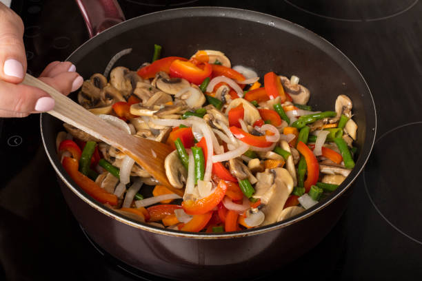 istock Stirring vegetables with mushrooms in a frying pan on a dark background 1003089536