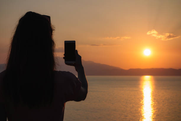 istock Woman photographing the sunset 1003094074