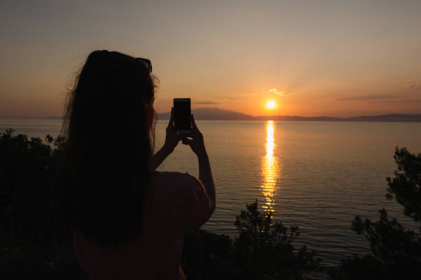 istock Woman photographing the sunset 1003097506