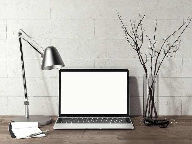 istock Laptop with blank screen on wooden table next to metal lamp, 3d rendering 1003111208