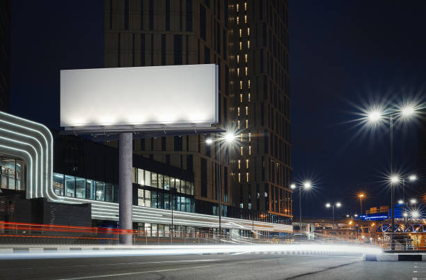 istock Blank illuminated billboard near well-lit road at night time. 3d rendering 1003112056