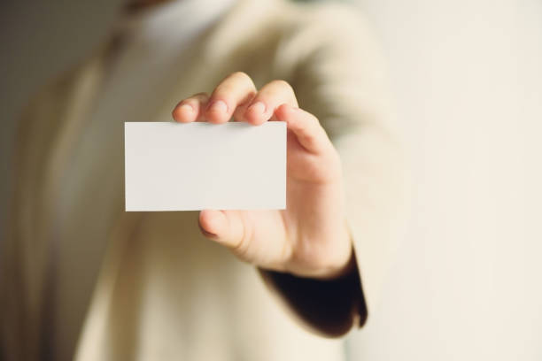 istock Businessman holding empty business card with copy space. Mock up. Business, study, network concept. Sunlight bokeh effect. Banner 1003115520