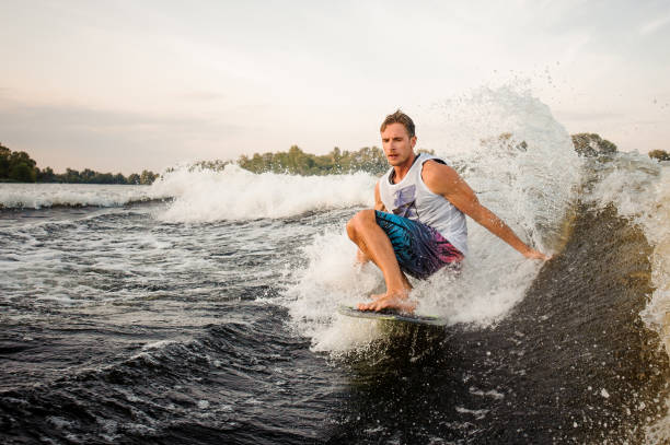 istock Handsome wakesurfer riding down the river on board 1003116032