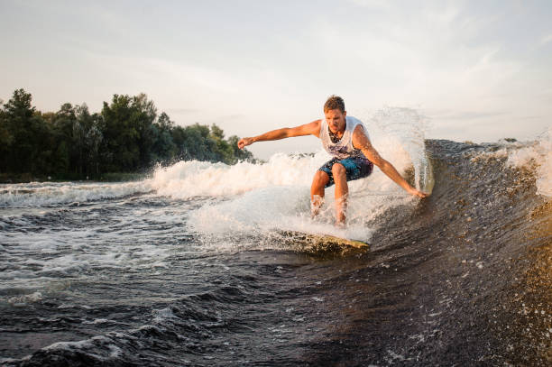 istock Muscular and strong wakesurfer riding down the river on board 1003118498