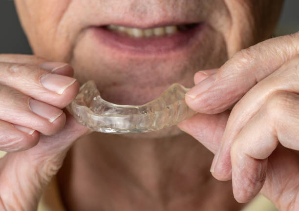 istock Senior man putting a night guard onto crooked teeth 1003122708