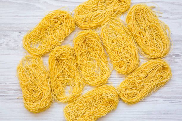 istock Uncooked pasta tagliolini on white wooden backgroundm top view. Flat lay, overhead. 1003125376