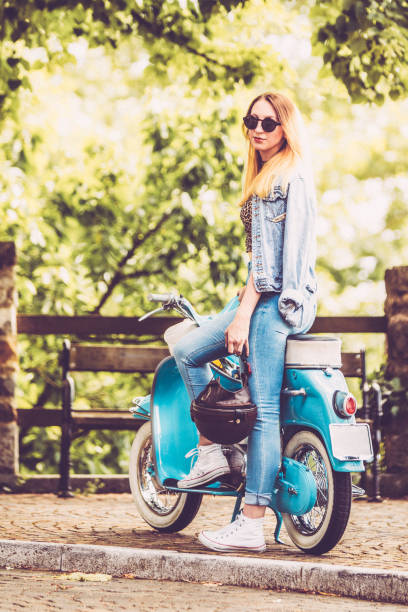 istock Young Smiling Woman and Her Old-fashioned Motor Scooter 1003127522