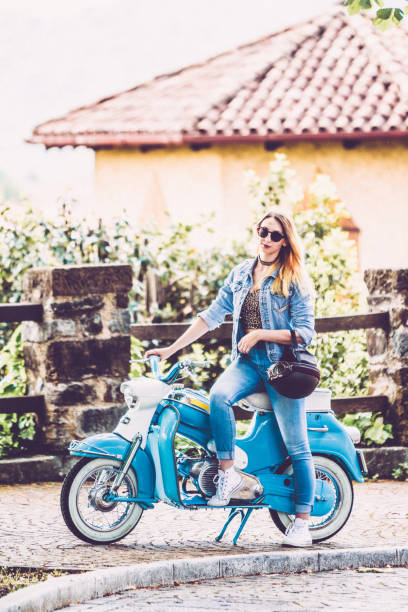 istock Young Smiling Woman and Her Old-fashioned Motor Scooter 1003127526